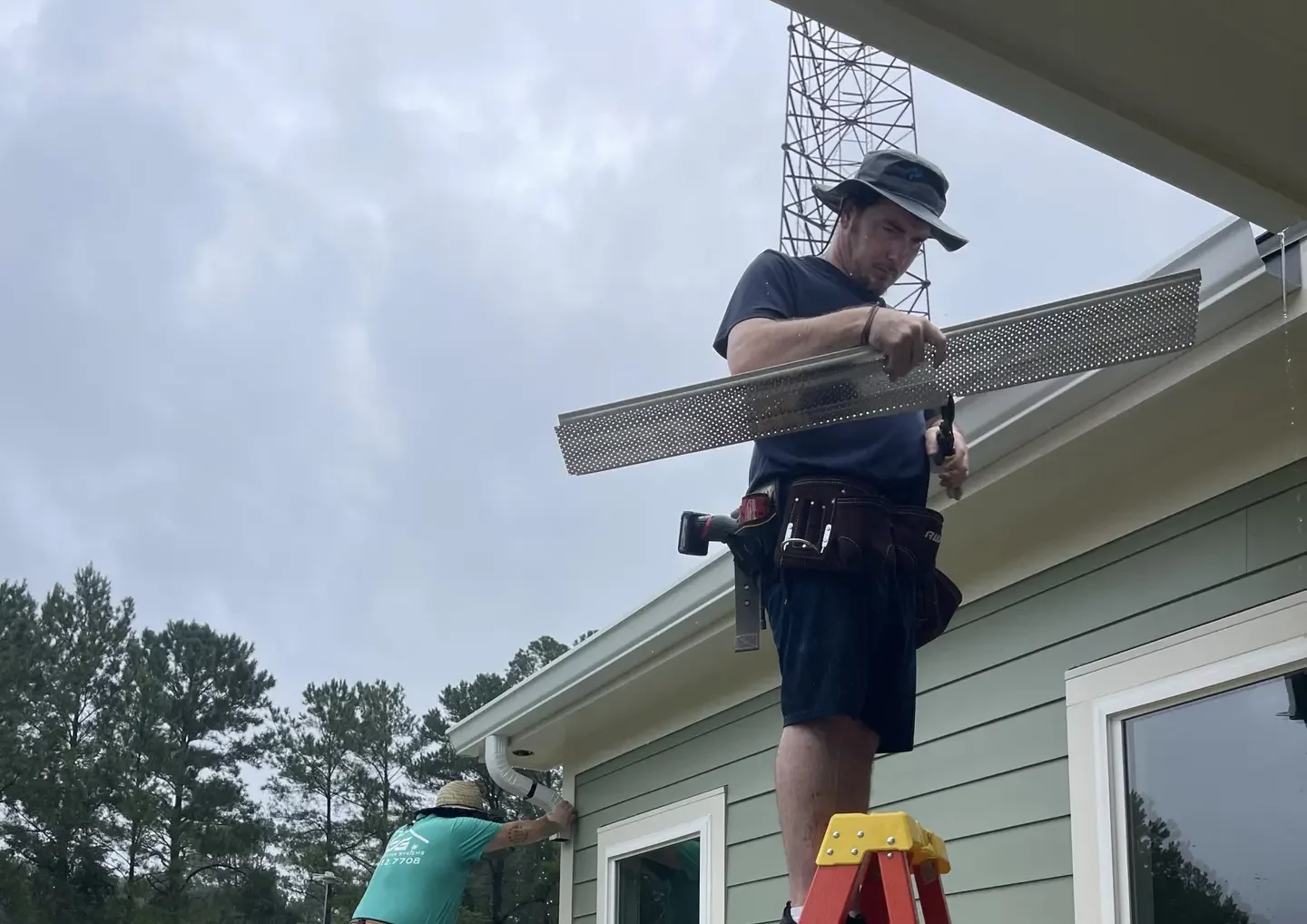 Two people installing gutters